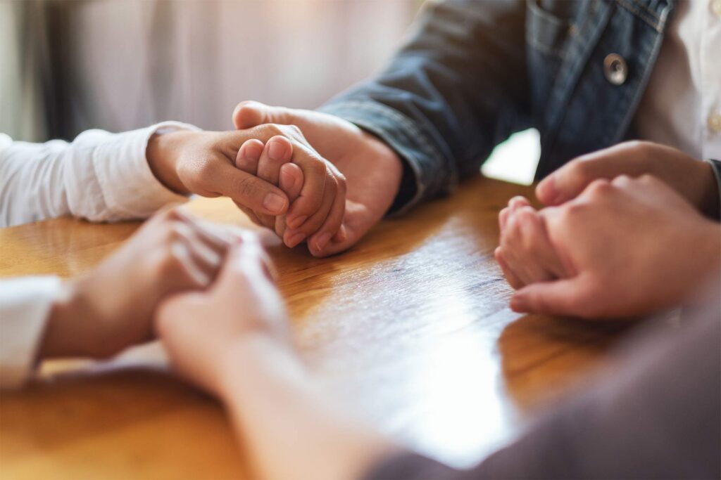 Two people holding hands in a supportive conversation
